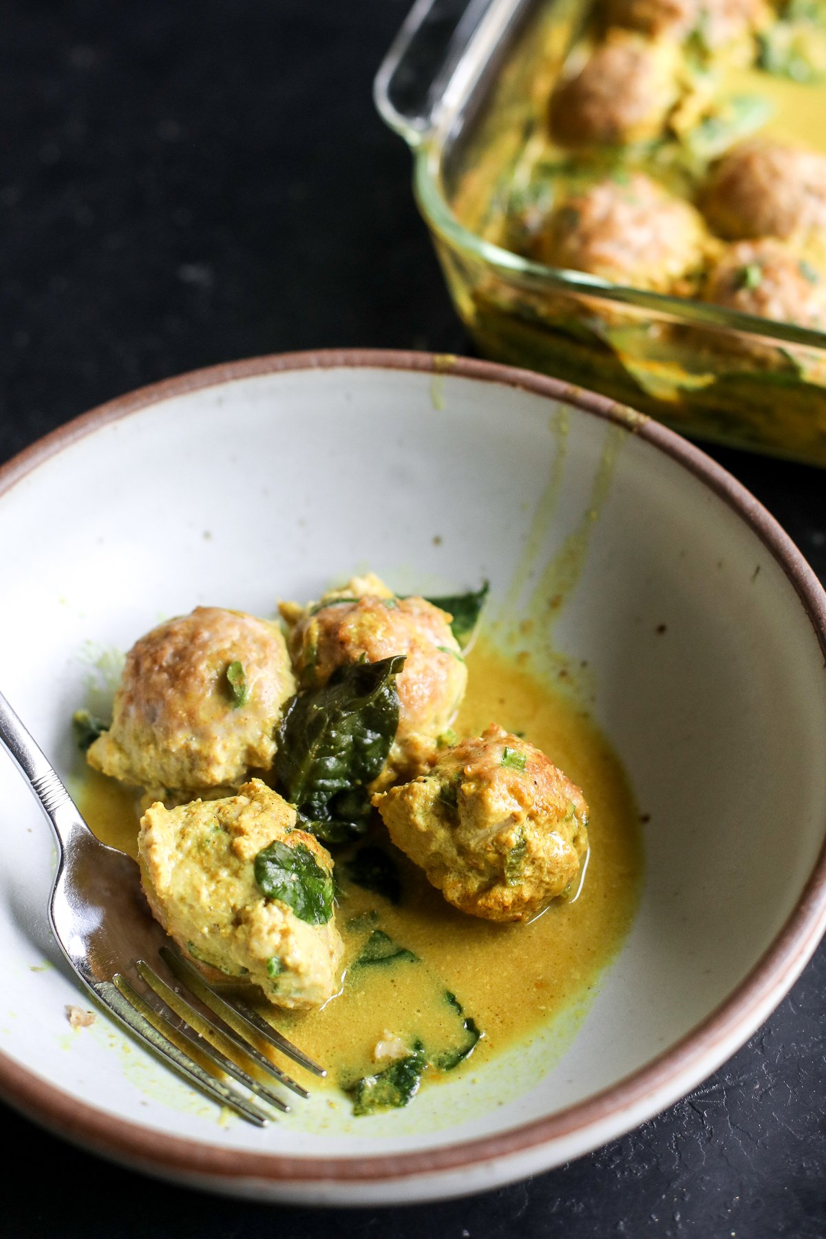 Easy one-pan dinner! Juicy chicken dumpling meatballs baked in a creamy, spinach-packed coconut curry sauce.
