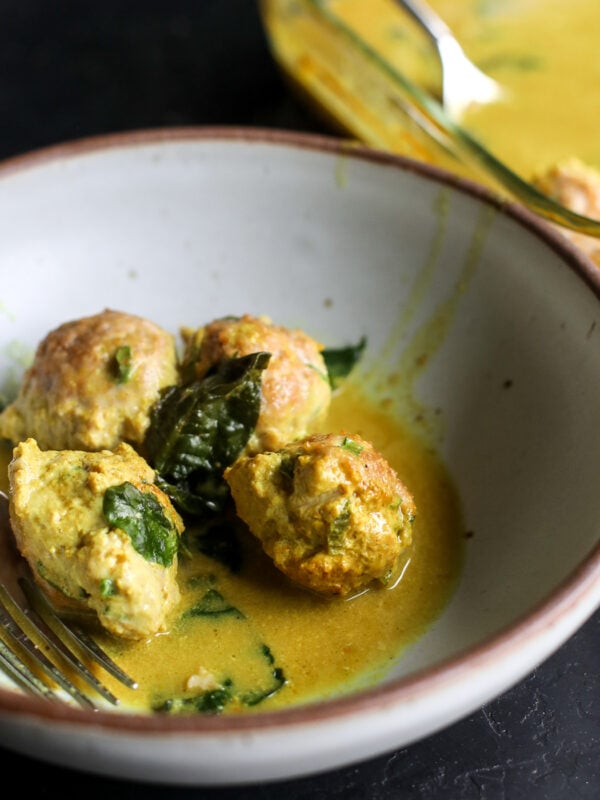Easy one-pan dinner! Juicy chicken dumpling meatballs baked in a creamy, spinach-packed coconut curry sauce.