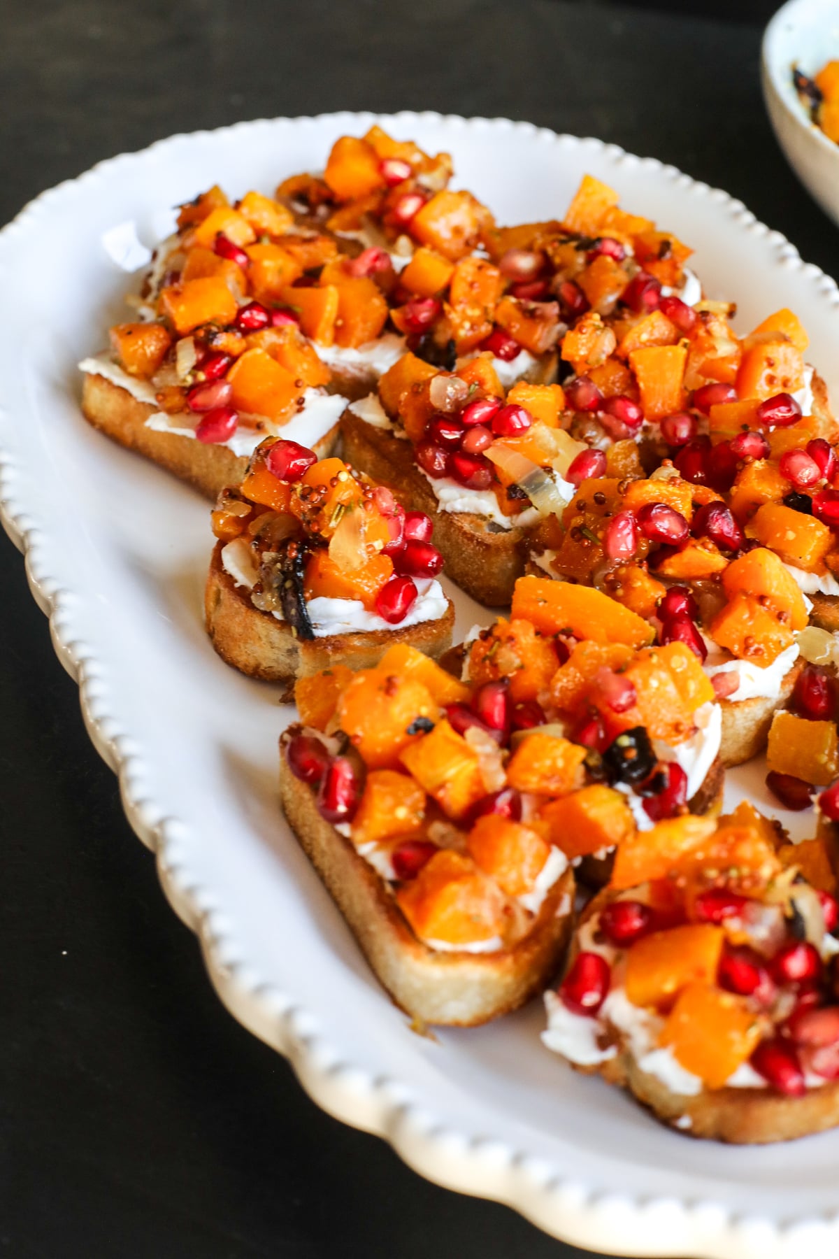 This Butternut Squash & Pomegranate Bruschetta is an easy holiday appetizer with creamy goat cheese, roasted squash and a tangy mustard dressing.