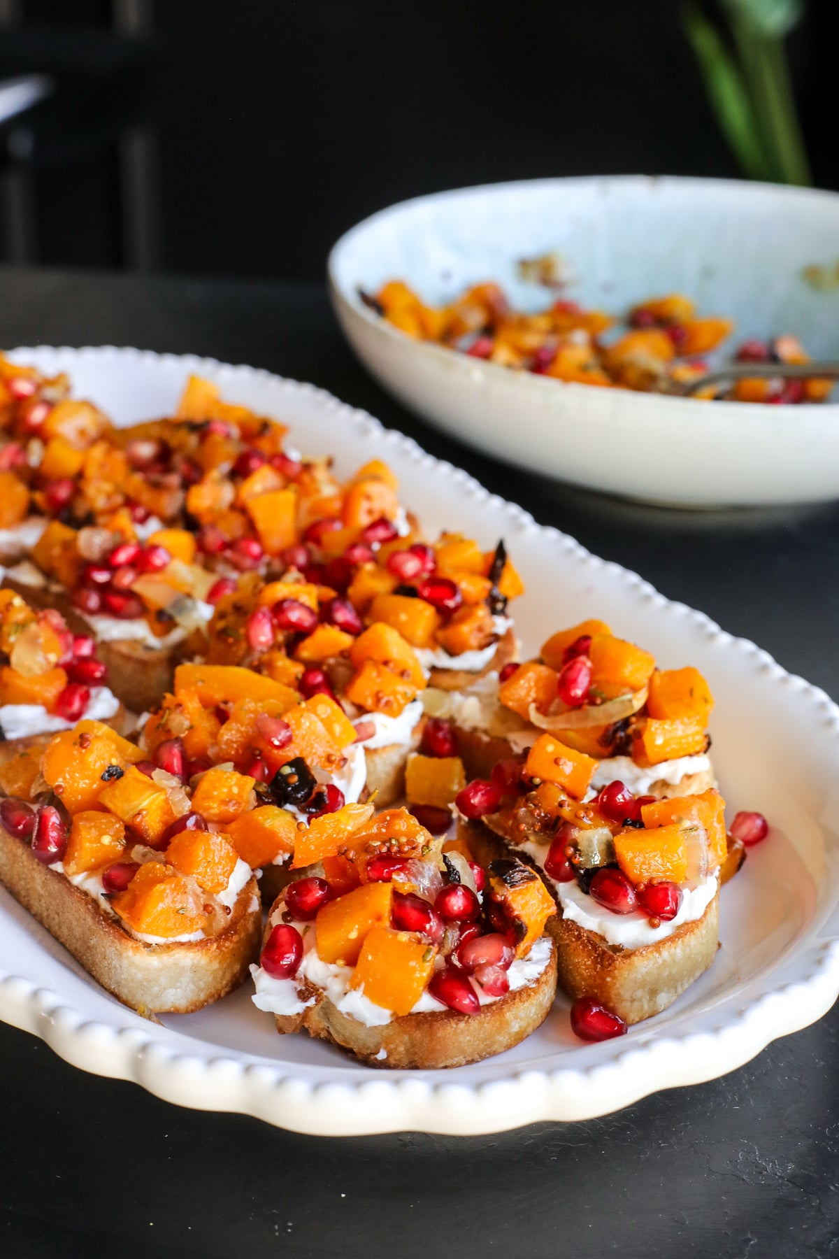 This Butternut Squash & Pomegranate Bruschetta is an easy holiday appetizer with creamy goat cheese, roasted squash and a tangy mustard dressing.