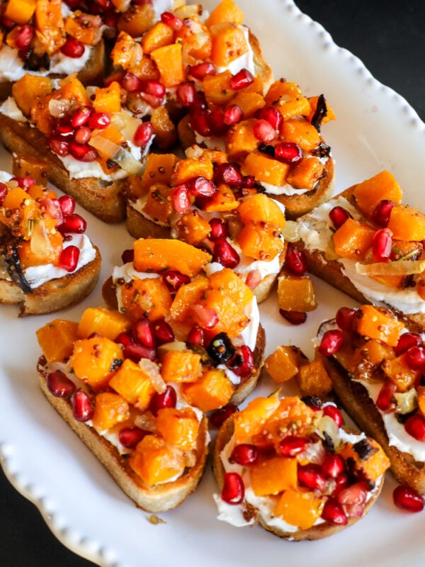 This Butternut Squash & Pomegranate Bruschetta is an easy holiday appetizer with creamy goat cheese, roasted squash and a tangy mustard dressing.